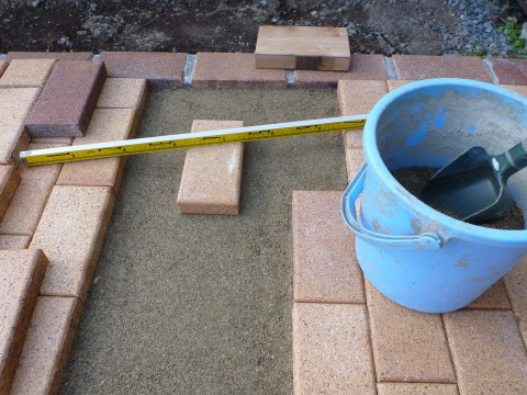 砂を足して、敷きレンガの凸凹を補修
