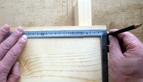 正確な寸法取りのために、板の端に鉛筆を立て、さしがねを当てる