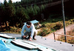 4寸勾配の屋根の上で、カラーベストコロニアルを釘打ち固定しているところ